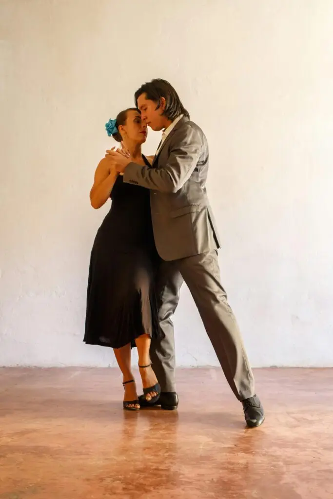 A couple gracefully performs a tango dance indoors, showcasing elegance and passion.