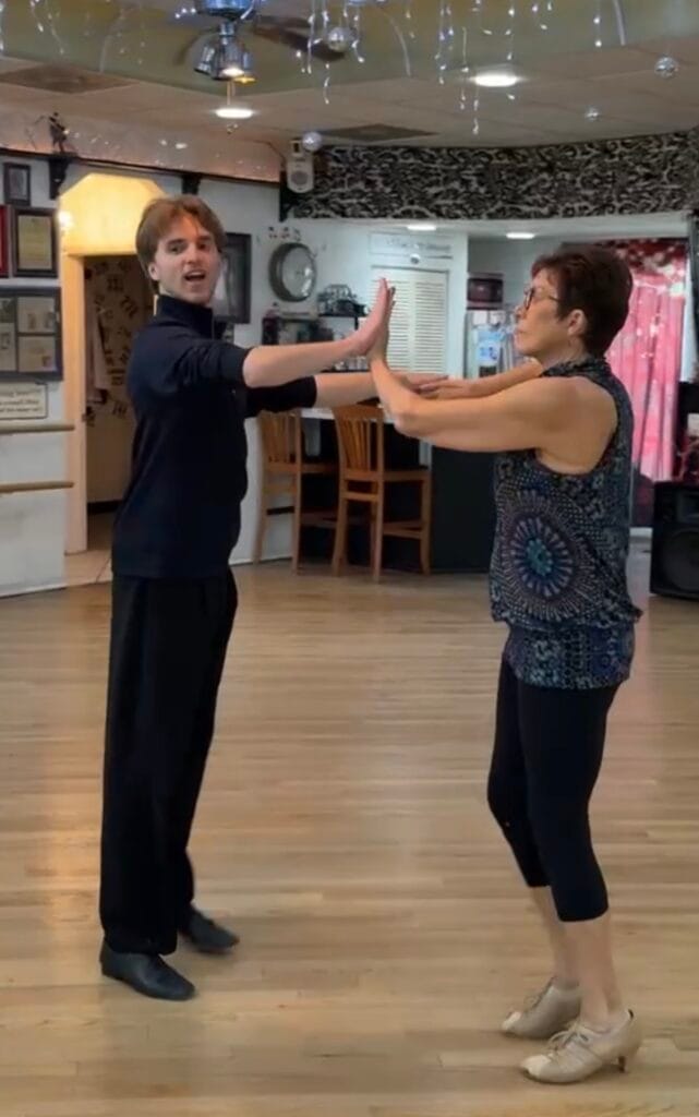 Happy woman dancing ballroom with instructor Dmytro Roshupkin, smiling and enjoying one of the best indoor activities Sarasota has to offer.